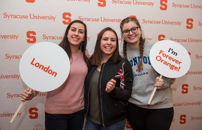 Three students holding London and Forever Orange signs.